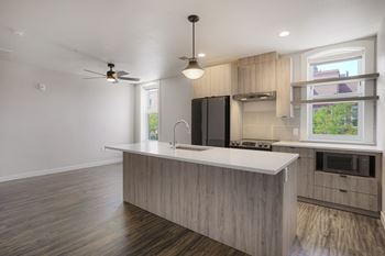 A modern kitchen with a wooden floor and a black refrigerator.